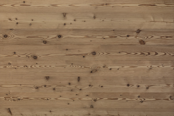 Mittelbraune Holzoberfläche mit ausdrucksstarker Maserung und lebendiger Aststruktur. Das Bild zeigt die gebürstete Variante von Piz Buin, die eine warme, alpine Ausstrahlung mit hochwertiger Haptik verbindet.