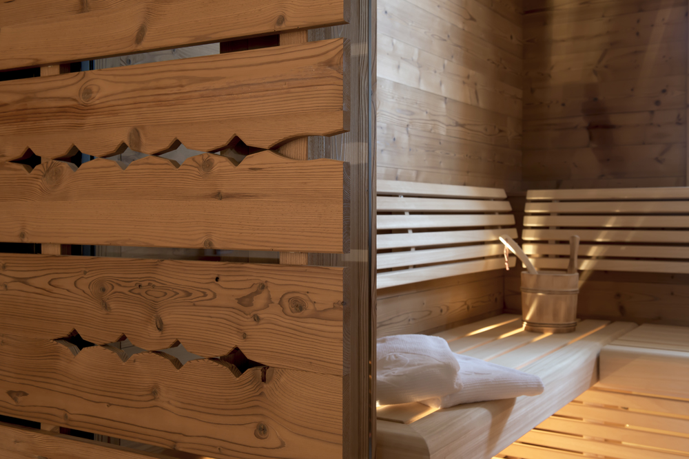 Hochwertig gestaltete Sauna in der Lech Lodge mit alpiner Wandpaneele „Gran Paradiso“. Feine Holzverarbeitung, traditionell ausgestanzte Ziermotive und harmonisch integriertes Licht sorgen für ein authentisches und entspanntes Saunaerlebnis.