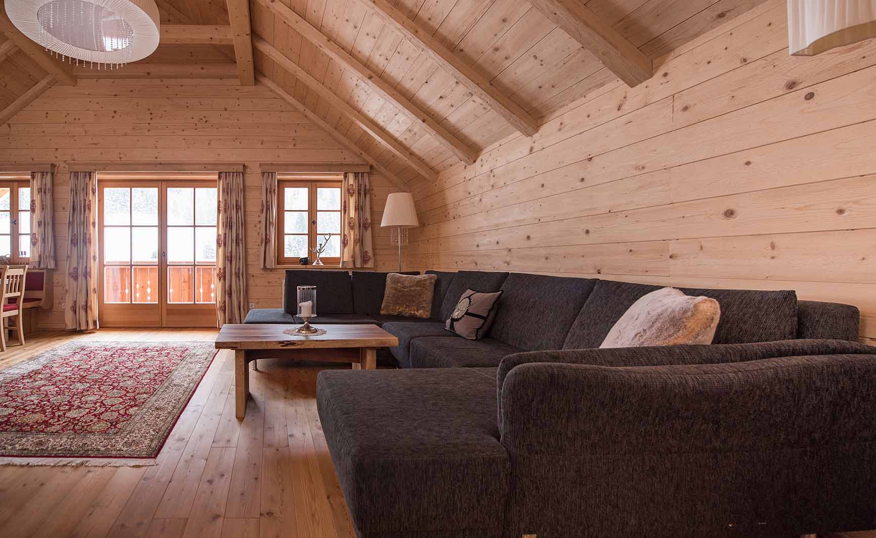 Gemütlicher Wohnraum mit Alpine Wandpaneelen Großglockner gehackt im Bergdorf Donnersbachwald – warme Holzoberflächen und Sichtdachstuhl schaffen alpines Ambiente mit Ausblick ins Freie.