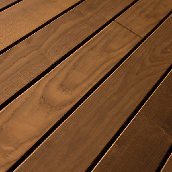 Terrassendielen mit glatter, gehobelter Oberfläche in einem satten, dunklen Braunton. Die ausgeprägte Maserung zeigt wellenartige Strukturen und sorgt für ein edles, modernes Erscheinungsbild mit natürlichem Charakter.