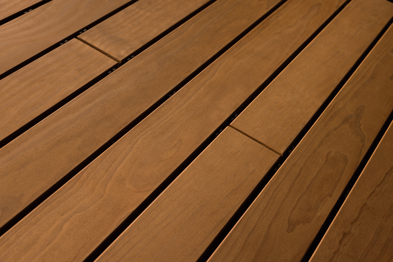 Terrassendielen mit gehobelter Oberfläche in einem satten, mittleren Braunton. Die glatte Struktur wirkt besonders edel und bringt die dezenten Maserungen sowie natürlichen Farbverläufe des Holzes fein zur Geltung.