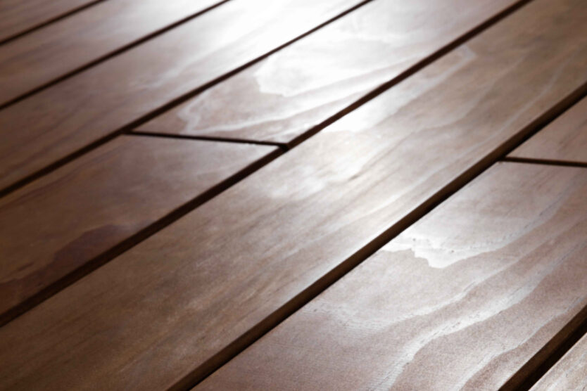 Makroaufnahme einer glatten, elegant schimmernden Holzterrasse aus Kebony-Holz in horizontaler Verlegung. Die Oberfläche zeigt natürliche Maserungen und eine warme, braune Färbung mit leichtem Glanz.