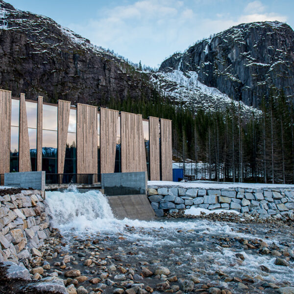 Zeitgenössisches Gebäude mit markanter vertikaler Holzfassade aus Kebony im Gebirge, direkt an einem Wildbach gelegen. Die Kombination aus natürlichem Holz, Glas und Beton betont Nachhaltigkeit und moderne Formensprache in alpiner Umgebung.