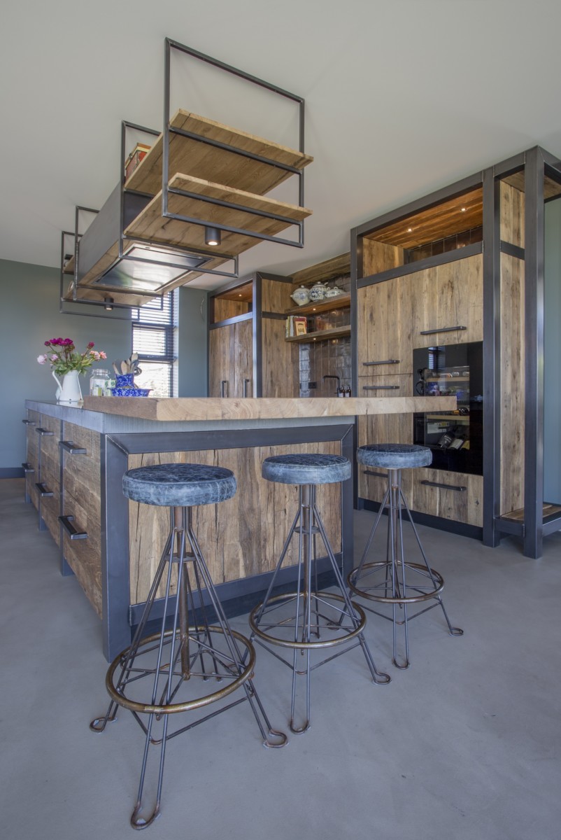 Moderne Küche mit Kücheninsel und Fronten aus Mareiner Altholz Sankt Moritz und Davos, kombiniert mit schwarzen Metallakzenten und Barhockern.