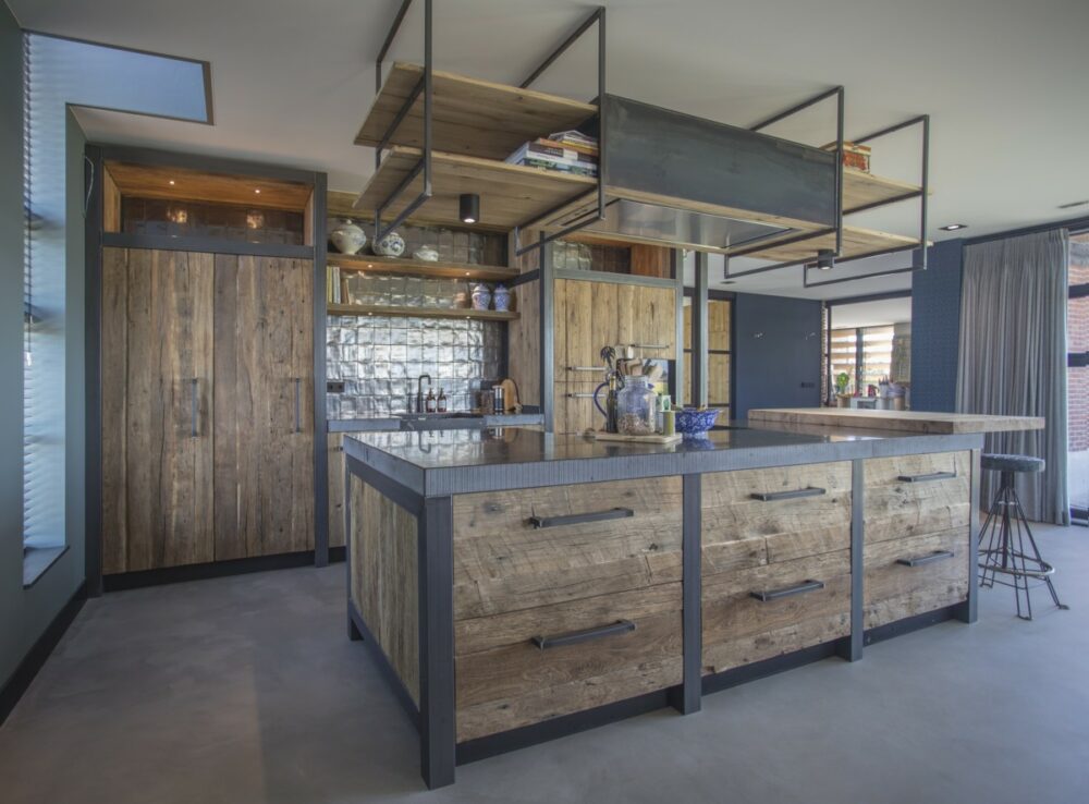 Küche mit rustikalem Charme, gefertigt aus Mareiner Altholz Sankt Moritz und Davos, kombiniert mit dunklem Stahl, modernen Geräten und einer glänzenden Arbeitsplatte.