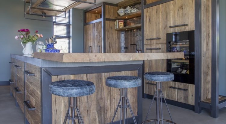 Moderne Küche mit Kücheninsel und Fronten aus Mareiner Altholz Sankt Moritz und Davos, kombiniert mit schwarzen Metallakzenten und Barhockern.