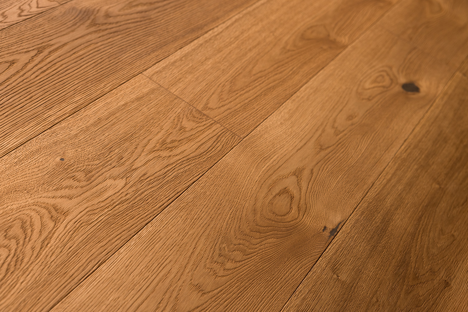 Warme Bodendielen mit markanter, natürlicher Maserung und vereinzelten Astlöchern. Die Oberfläche zeigt eine fein strukturierte Holztextur, die rustikale Eleganz mit wohnlicher Atmosphäre vereint – ideal für stilvolle Innenräume.