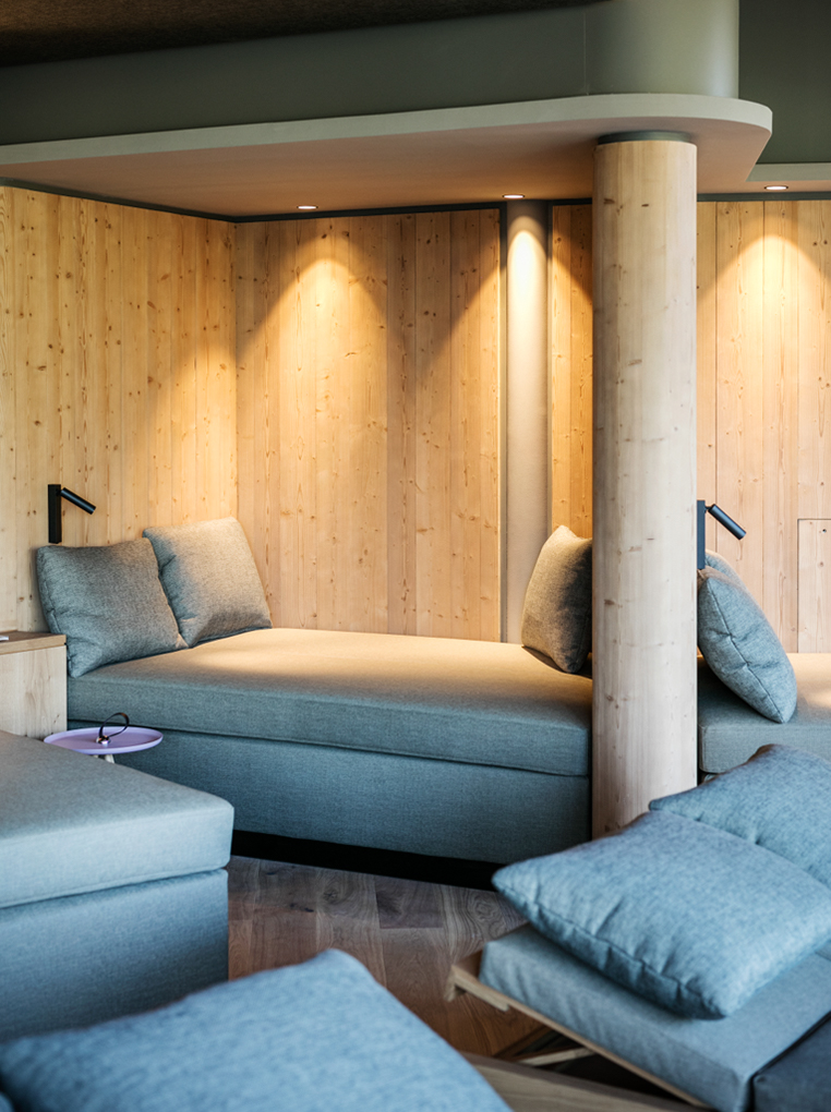 Stilvoller Ruheraum mit gemütlichen Liegeflächen in Blautönen und Wänden aus Mareiner Holz Zugspitze. Warmes Licht und natürliche Materialien schaffen eine entspannte Atmosphäre im Almwellness Hotel Pierer.