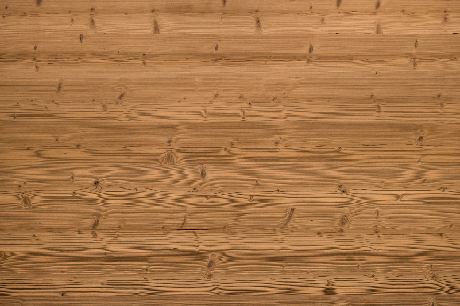 Gebürstete Holzoberfläche mit betonter Maserung und feinen Jahresringen. Warme, mittelbraune Farbgebung mit deutlich sichtbaren kleinen Astlöchern und natürlicher Struktur. Die Oberfläche wirkt lebendig und strukturiert.