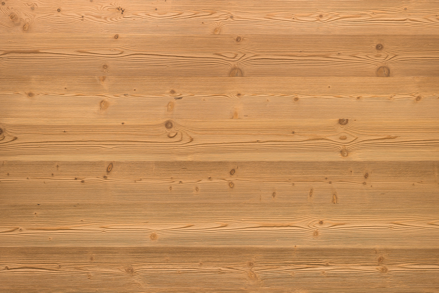 Gebürstete Holzoberfläche mit natürlicher Maserung und feiner Struktur. Die hellbraunen Dielen zeigen Astlöcher und Jahresringe, was dem Holz ein lebendiges und authentisches Aussehen verleiht.