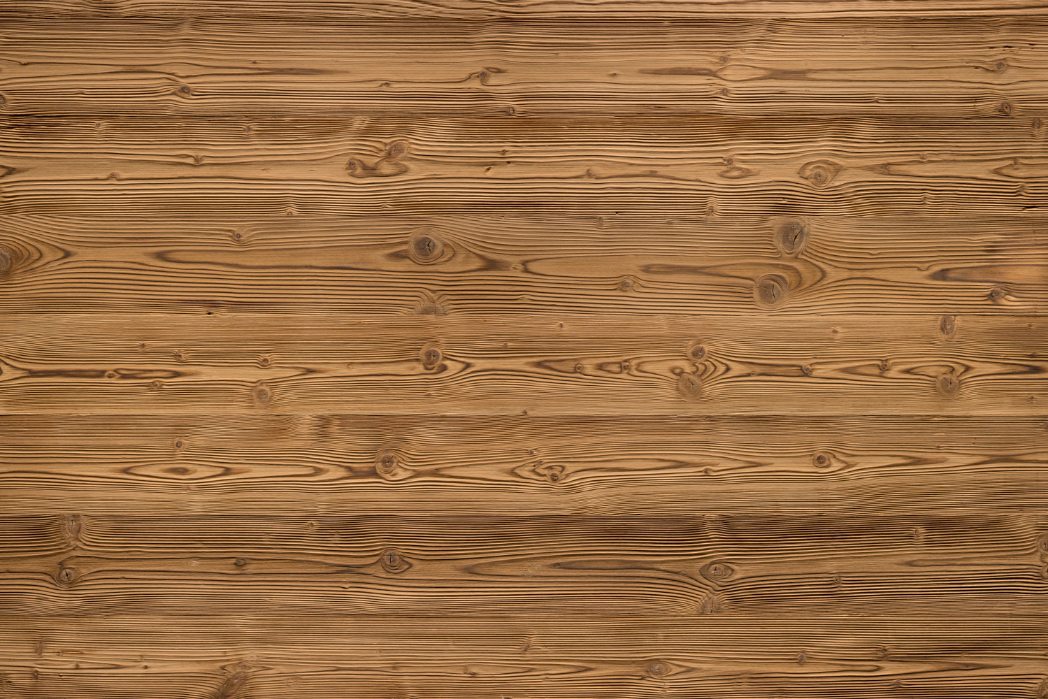 Geflammte Holzoberfläche mit starker Maserung und dunklen Flammenakzenten. Die Bretter zeigen markante Jahresringe und Astlöcher, die dem Holz einen rustikalen, lebendigen Charakter verleihen.