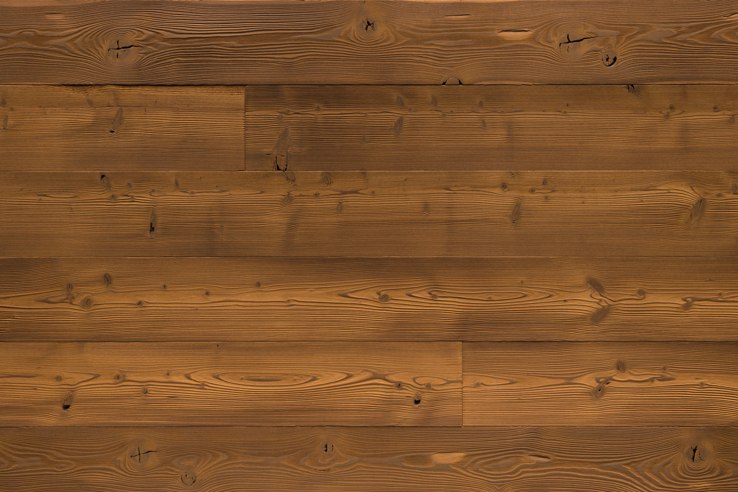 Dunkel gebürstete Holzoberfläche mit deutlicher Maserung und sichtbaren Astlöchern. Die strukturierte Oberfläche verleiht dem Holz eine natürliche Tiefe und Haptik, ideal für rustikale oder moderne Wohnräume mit Charakter.