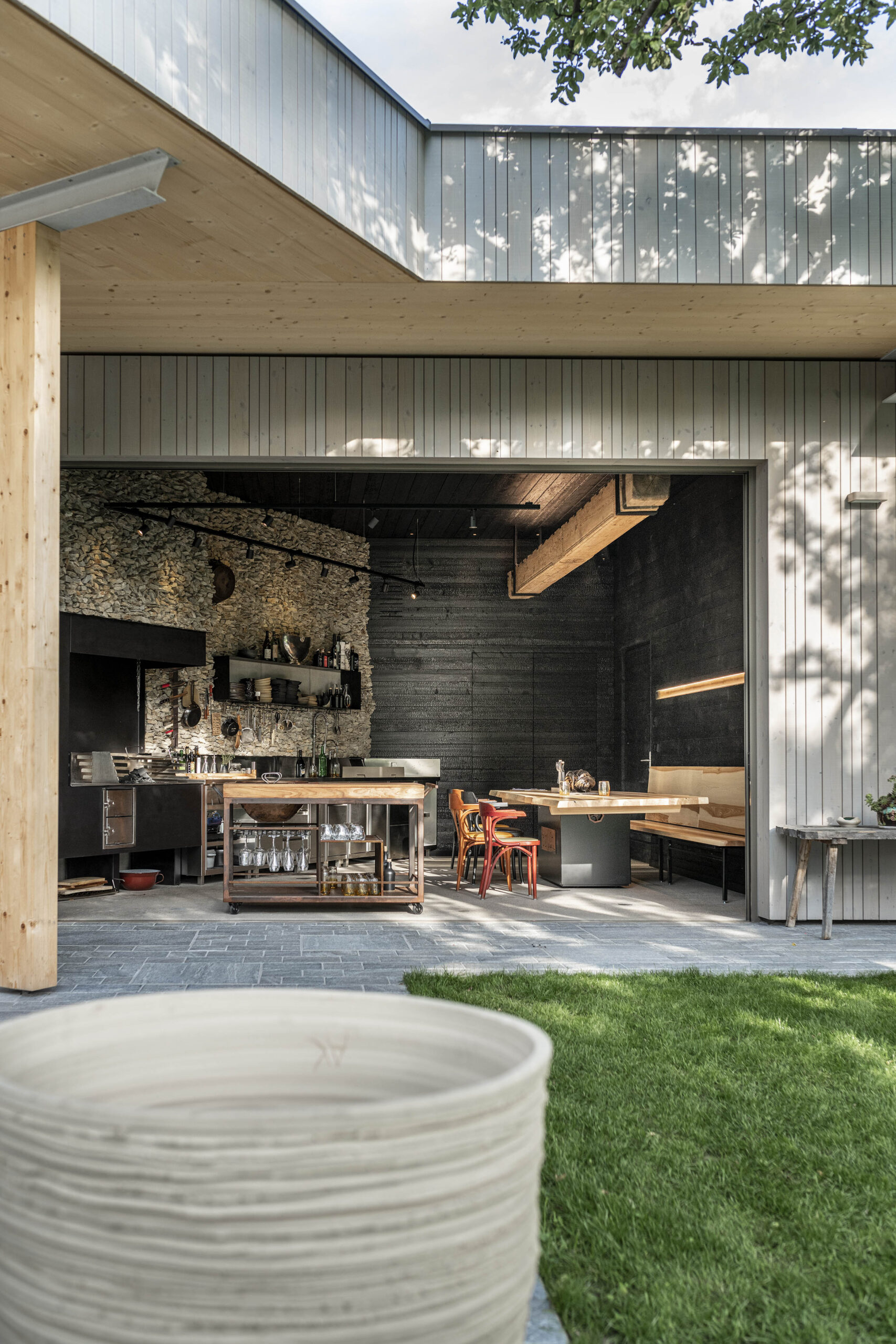 Blick in die offene Gastroküche des Hotel Restaurant Krainer. Außenfassade in „Wörthersee beschichtet“, Innenwände aus verkohltem Mareiner Vulcano-Holz. Naturstein, Massivholzmöbel und moderne Ausstattung schaffen ein hochwertiges, naturnahes Ambiente.